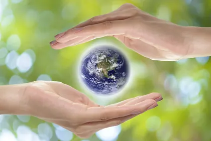 Deux mains entourent une petite Terre lumineuse