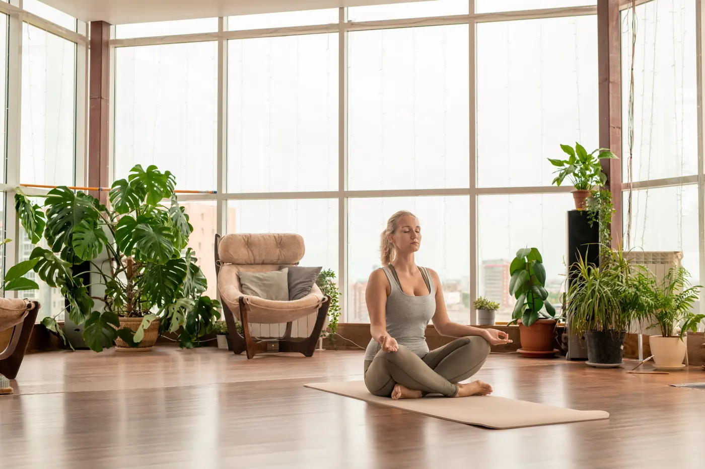 Une femme médite dans un salon lumineux plein de plantes